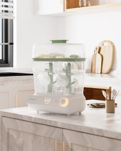 Momcozy three layer bottle sterilizer and dryer with baby bottles on a kitchen counter