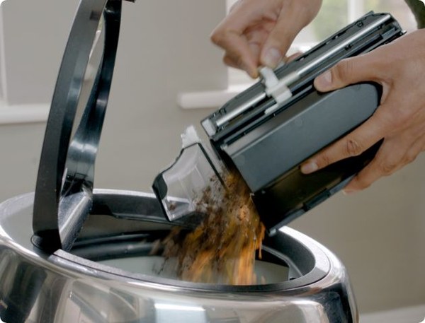 Hands emptying the Gtech AirRAM 3 bin into a kitchen bin