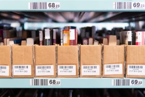 How to Build a Home Library on a Budget Rows of labelled boxes filled with second-hand books on warehouse shelves