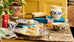 Blue Hen pottery jug, bowls and plates laid out on a rustic kitchen table