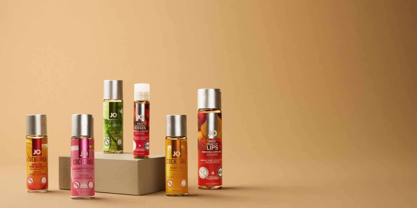 Selection of flavoured personal lubricant bottles on a beige background