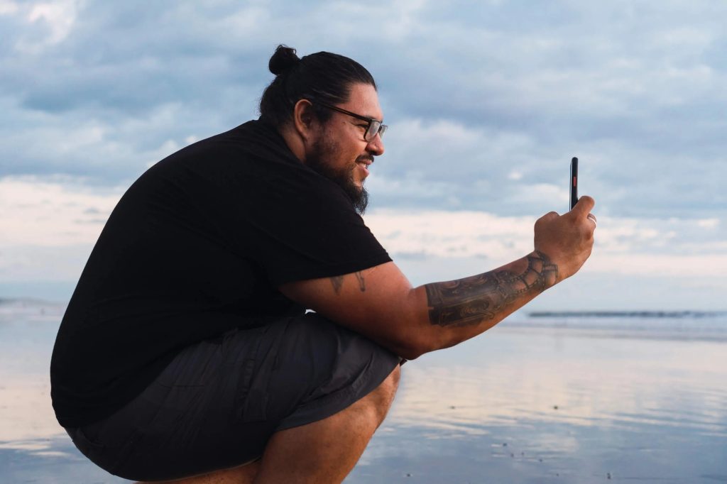 Man taking a photo on a beach at sunset