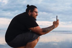 Man taking a photo on a beach at sunset