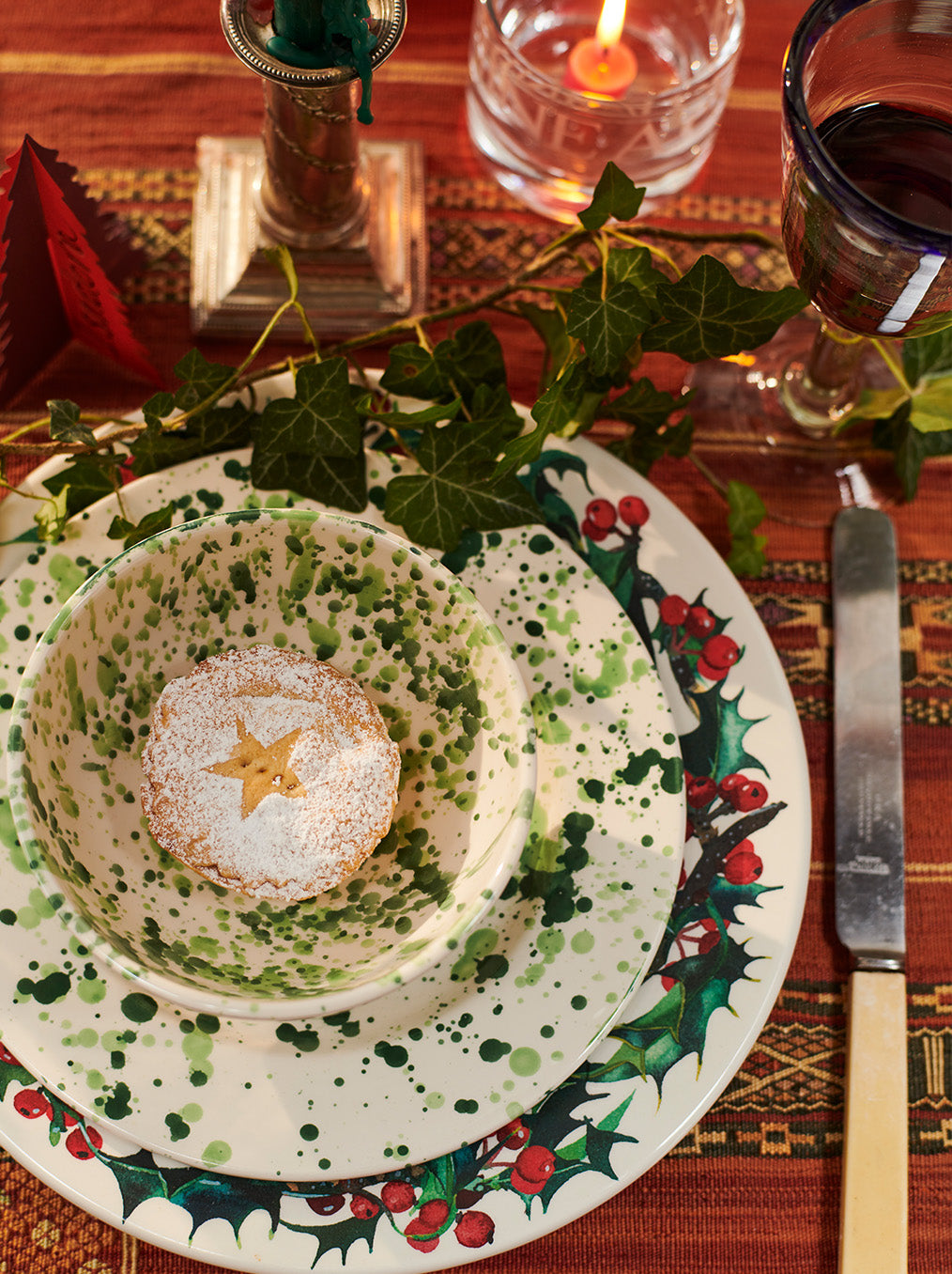 Festive place setting with holly plate, green splatter bowl and a mince pie