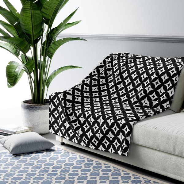LIT Mono Sherpa blanket in a black and white pattern draped over a sofa