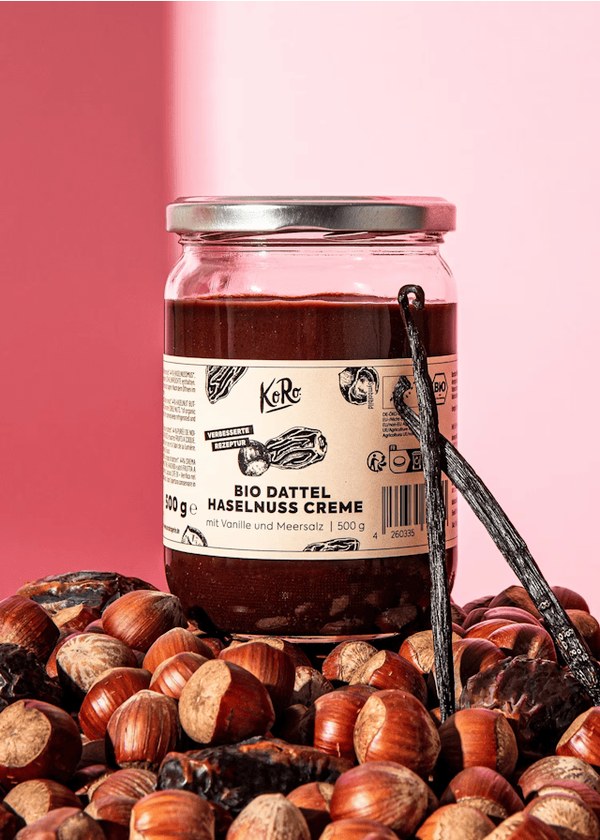 KoRo organic date and hazelnut cream jar on a pile of hazelnuts and dates
