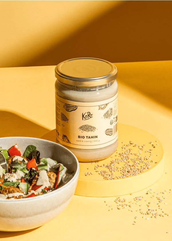 KoRo organic tahini jar beside a bowl of salad and sesame seeds