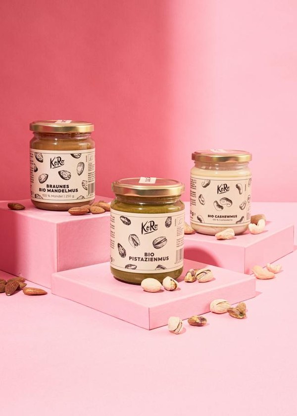 Three KoRo nut butter jars on pink steps, representing a tasting set