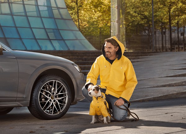 Woman with a dog standing beside a car