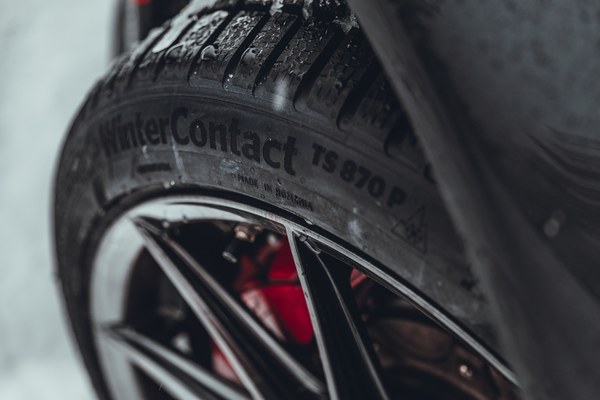 Close-up of a Continental winter tyre sidewall with a red brake caliper behind it