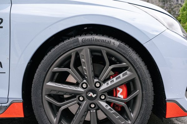 Alloy wheel with a tyre and a red brake caliper on a light coloured car