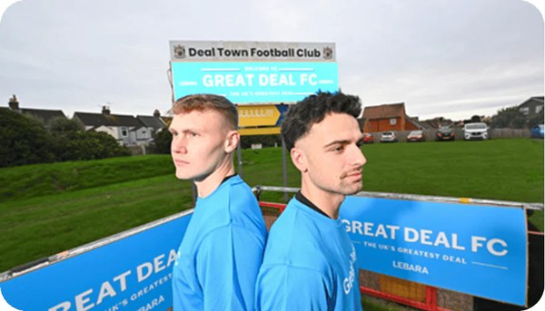 Two footballers in blue kits by a Lebara Great Deal FC sign