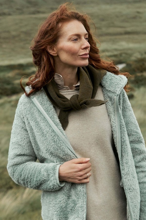 Model wearing the Weird Fish Ballamy textured knitted triangle scarf in oak green