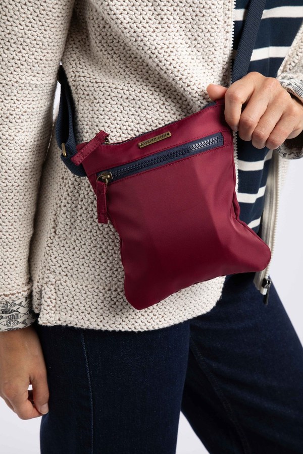 Model carrying the Weird Fish Nisla crossbody bag in red grape